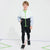 A young boy modeling a color-blocked zip-up jacket, black shorts, and black leggings with athletic shoes, standing on a white studio floor with colored lines.