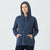 A woman wearing a navy blue knit pullover hoodie with drawstrings and front pockets, standing against a light gray studio background.