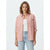A woman modeling a light pink button-up shirt with rolled-up sleeves, worn open over a white tank top and light-wash blue jeans, against a plain light gray studio background.