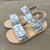 Pair of sandals with floral straps on a concrete floor