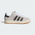 Beige Adidas sneaker with black stripes on a light gray background