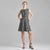 A woman modeling a sleeveless black and white micro-check patterned dress with a V-neckline and front zipper, paired with black high-heeled sandals, against a solid gray studio background.