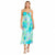 A woman modeling a sleeveless midi dress with thin straps and a watercolor floral print in shades of turquoise, green, and purple, paired with beige strappy high-heeled sandals against a plain white background.