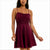 A woman wearing a sleeveless, skater-style mini dress in deep burgundy with a gathered bodice and thin shoulder straps, shown against a plain white background.