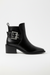 Black ankle boot with metallic buckle on a white background