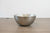 Metallic bowl with textured surface on a wooden surface