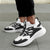 Black and white sneakers worn on a gray pavement