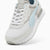 A Puma sneaker in white and light gray with a light blue side stripe, shown from a three-quarters angle on a white background.