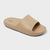 A single beige slide sandal with a thick, cushioned sole and a wide strap, shown from a three-quarters angle on a light gray background. The brand name 'GoodLife' is printed in black on the heel area of the footbed.