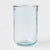 A clear light blue-tinted glass tumbler with a thick, rounded base, photographed against a seamless white background.