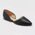 Black pointed-toe flat shoe on a light gray background