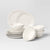 Set of white ceramic dinnerware including plates and bowls on a light gray background
