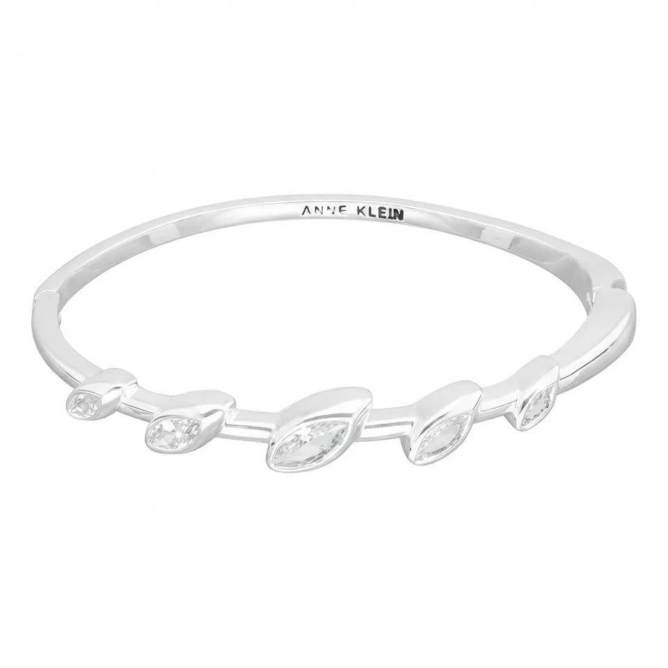 A silver bangle bracelet by Anne Klein, featuring a polished band with five marquise-cut clear gemstones arranged in a row, set against a plain white background.