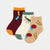 Three ankle socks laid flat on a light gray background: one burgundy with orange toe and cuff, one cream with green cuff and green insect print, and one beige with yellow text and red/blue insect and flower prints.