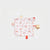 A square baby sensory lovey cushion with a white background and a red and beige Christmas print, featuring a red tab, a gold star, and a 'Merry Everything' brand tag, photographed on a light gray background.