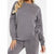 A woman wearing a matching gray sweatshirt and sweatpants set, cropped from the neck down, against a plain white background.