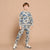 A young boy modeling a light gray two-piece tracksuit with a blue and black graphic print, standing against a solid beige background.