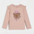 A light pink long-sleeve t-shirt for girls, featuring ruffled shoulders and a central graphic of a brown cartoon bear wearing a pink beanie and bow tie, with the text 'COD. AND CLASITY' printed next to it.