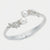 A silver-toned hinged cuff bracelet featuring two white pearls and diamond-encrusted floral motifs on each side, shown on a light gray background.