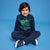 A young boy sits cross-legged on a solid blue studio background, wearing a navy blue sweatshirt with a green video game controller graphic and the text 'GAME OVER THE LOST PLAYER' paired with navy pants and sneakers.