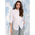 A woman wearing a white long-sleeve button-up shirt and light gray jeans, standing against a textured blue and white background.