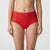 A model wearing red lace high-waisted briefs against a plain light gray studio background.