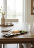 Sushi on a wooden table with a glass of water and a vase in the background.