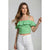 A woman modeling a green and white gingham off-the-shoulder ruffle crop top with white jeans, set against a plain light gray studio background.