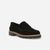 A single black suede loafer with a chunky black sole and a natural tan midsole layer, shown from a three-quarters angle on a light gray background.