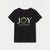 A black short-sleeve t-shirt with a festive Christmas graphic on the front. The graphic spells 'JOY' in white letters, where the 'O' is replaced by a green wreath with a red bow, and the text 'to the world at Christmas time' is written below in white script.