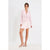 A woman modeling a light pink double-breasted blazer and matching mini skirt set, paired with light pink heeled sandals, against a plain white studio background.