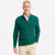 A man wearing a dark green quarter-zip knit sweater over a cream collared shirt and khaki pants, standing against a plain white studio background.