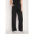 Black wide-leg pants with a white side stripe, modeled with a black top and white sneakers against a light gray background.