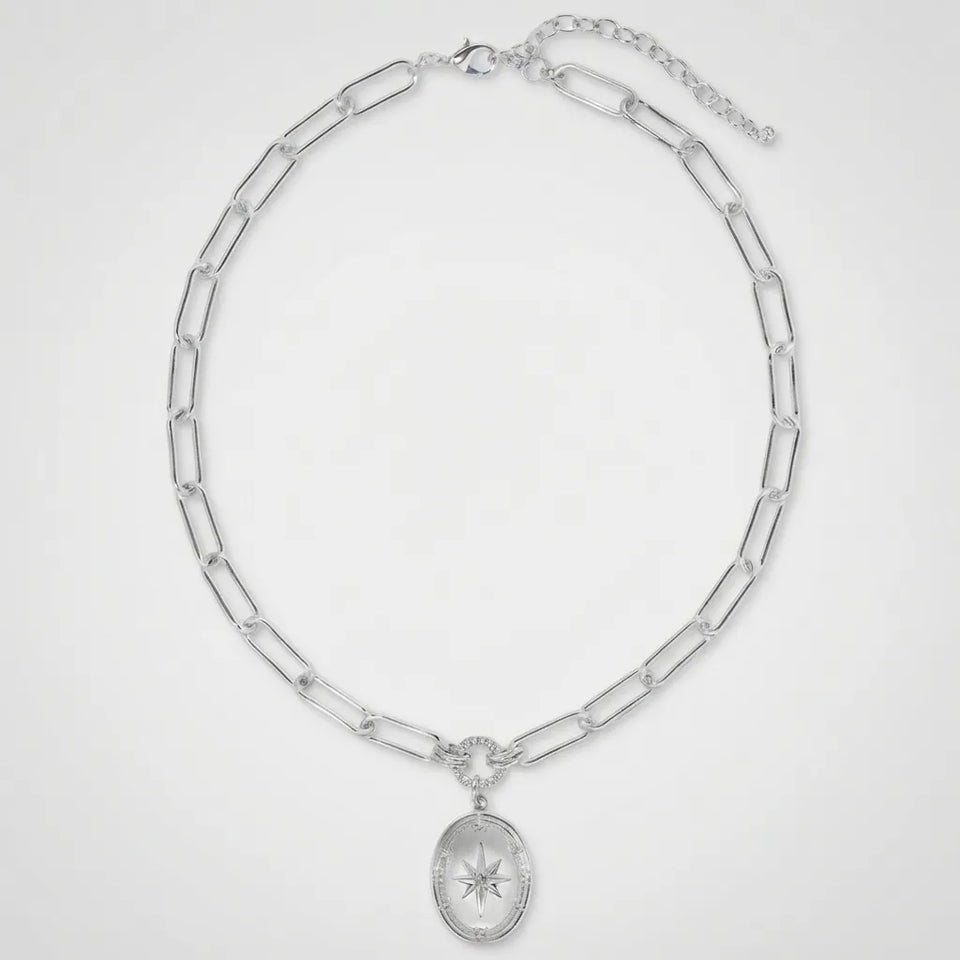 A silver-toned paperclip chain necklace with an oval pendant featuring a starburst motif, displayed on a clean white background.