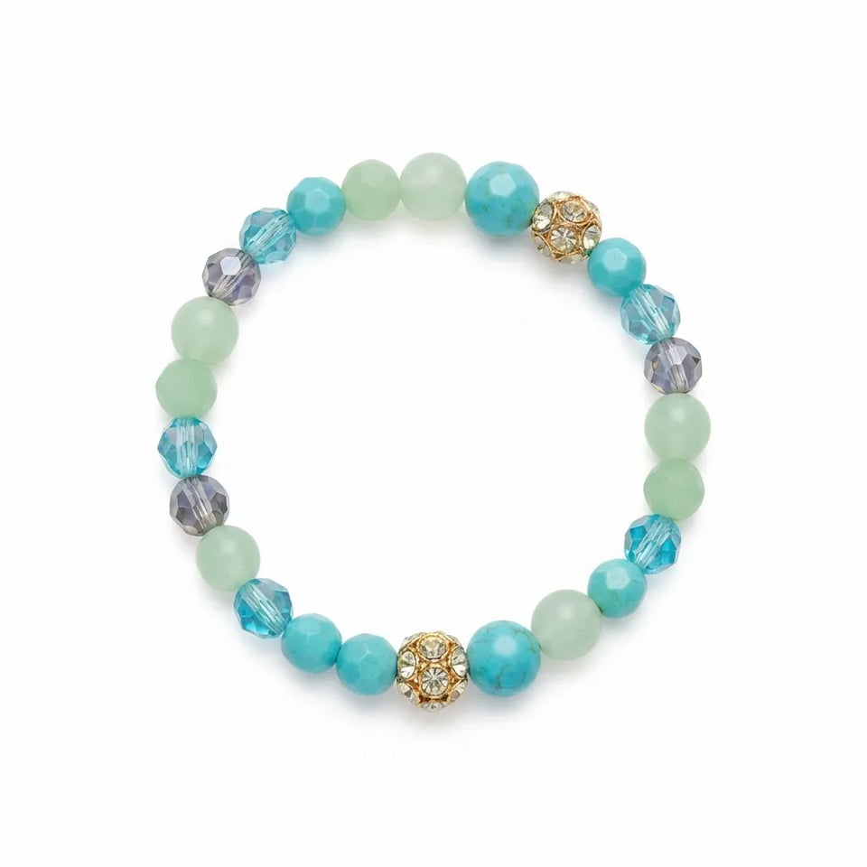 A beaded stretch bracelet featuring light blue faceted beads, pale mint green matte beads, and two gold-toned decorative floral beads with clear rhinestones, displayed on a clean white background.