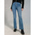 A person wearing blue high-rise flare jeans with a button fly, styled with a black long-sleeve top and black platform boots against a light gray studio background.