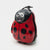 A red and black ladybug-shaped rolling suitcase with a smiling cartoon face on the front, shown on a plain light gray background.