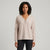 A woman modeling a light beige ribbed knit long-sleeve henley sweater with a buttoned V-neck, paired with black pants, against a light gray studio background.
