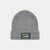 A heather gray ribbed knit beanie hat with a folded cuff, featuring a black rectangular patch on the front with a green and white graphic.