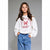 A young girl with long brown hair stands against a solid gray studio background wearing a white sweatshirt with a red 'Gingerbread Bakery' graphic and blue jeans.