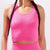 A close-up of a model wearing a bright pink ribbed athletic crop top and matching high-waisted bottoms against a light gray background.
