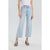 A model wearing light-wash blue cropped wide-leg jeans, paired with a white ruffled top and black strappy heels, shown against a light gray studio background.