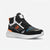A black high-top athletic sneaker with white and gray panels, orange accents, and a textured white sole, shown against a light gray background.