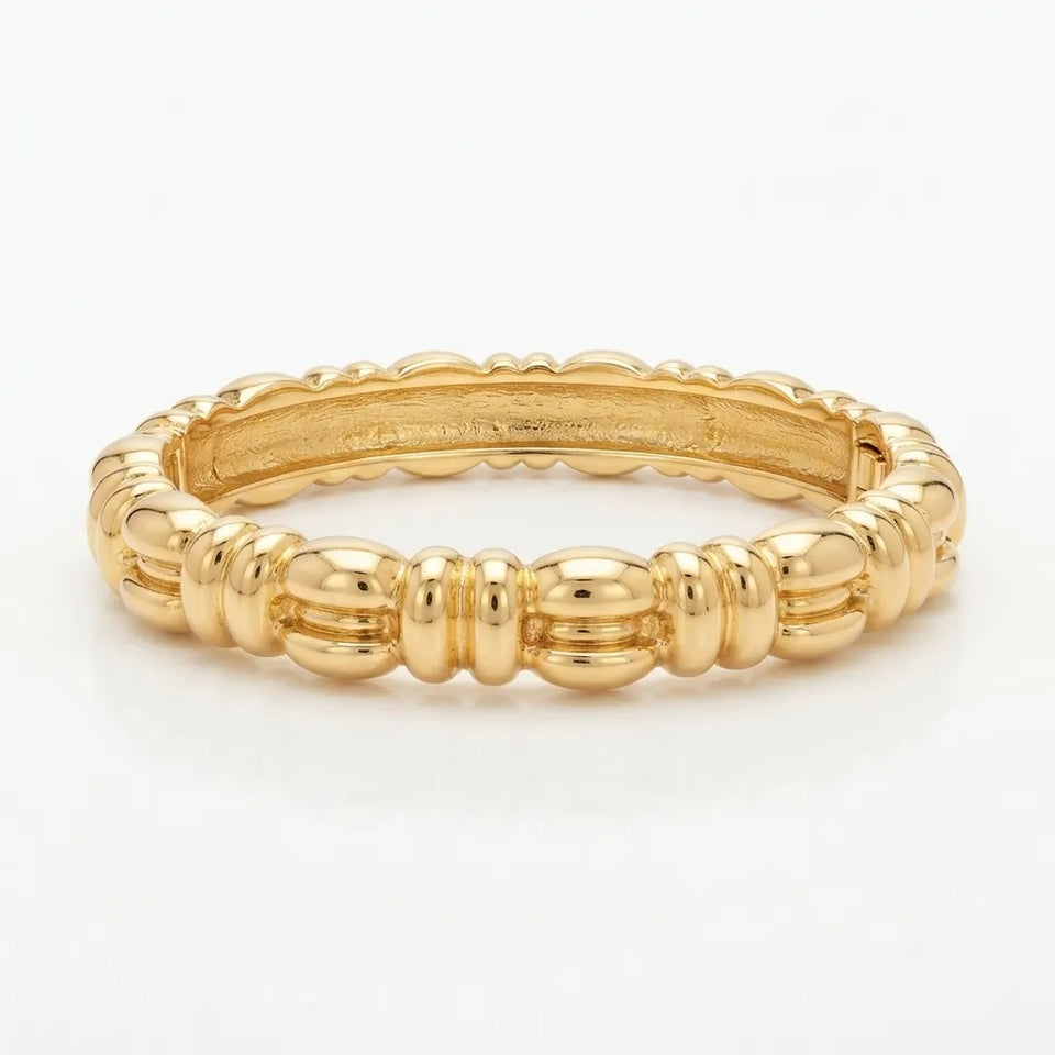A polished yellow gold bangle bracelet with a textured, ribbed design, displayed on a clean white background.
