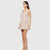 A woman modeling a sleeveless, square-neck mini dress in a light beige or nude color, featuring a structured waist and a flap pocket on the left side, set against a solid light gray background.
