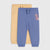 Two pairs of children's sweatpants, one in dusty blue with a dinosaur patch and front pocket, and one in pale yellow, displayed flat against a light gray background.