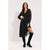 A woman models a black long-sleeve midi dress with a white polka-dot pattern, paired with black over-the-knee boots, against a plain light gray studio background.