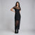 A woman modeling a black lace midi dress with short sleeves and sheer lace overlay panels, paired with black ankle boots, against a light gray studio background.