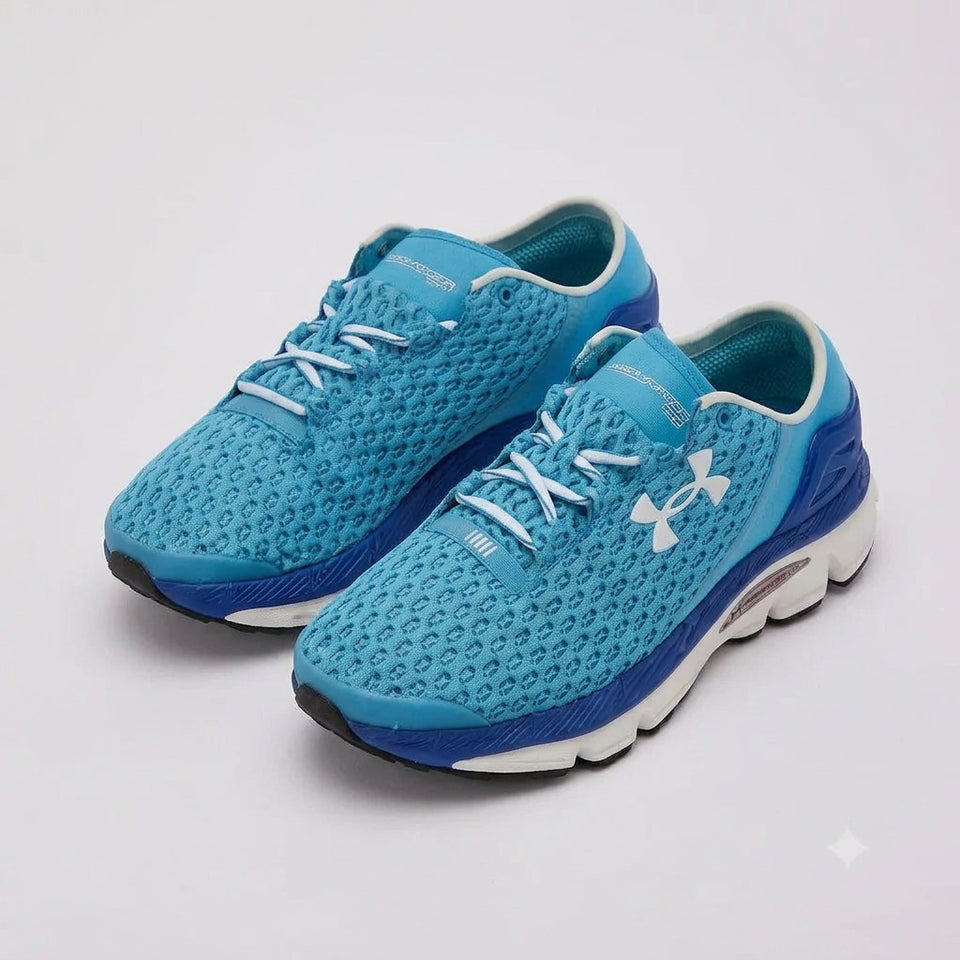 A pair of Under Armour athletic sneakers in bright blue and navy with white accents, shown on a light gray studio background.