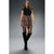 A woman modeling a black short-sleeve top, a brown and beige patterned pleated mini skirt, sheer black tights, and black over-the-knee boots, standing against a dark gray studio background.